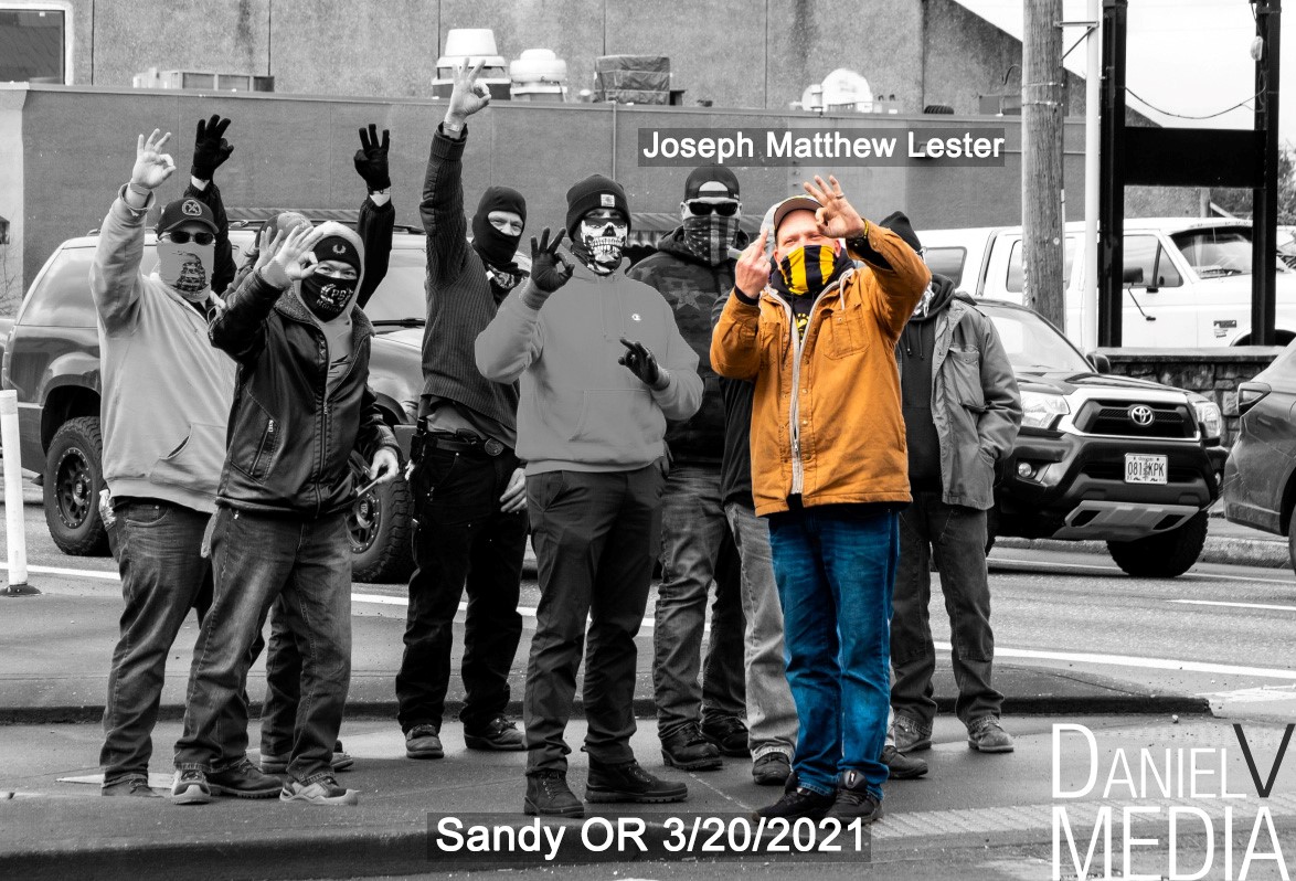 A Black and white photo of proud boys on a street corner in Sandy Oregon. Joey Lester is show in color. He is dressed in a brown jacket. 